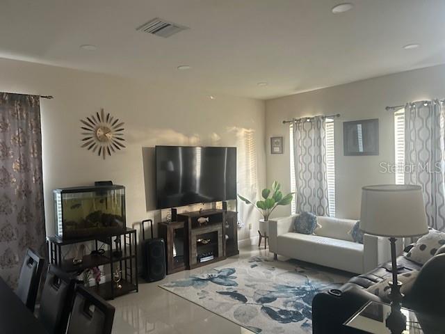 A living room features a large television, a fish tank, and a patterned area rug — 34809 PRAIRIE RIDGE WAY, ZEPHYRHILLS, FL