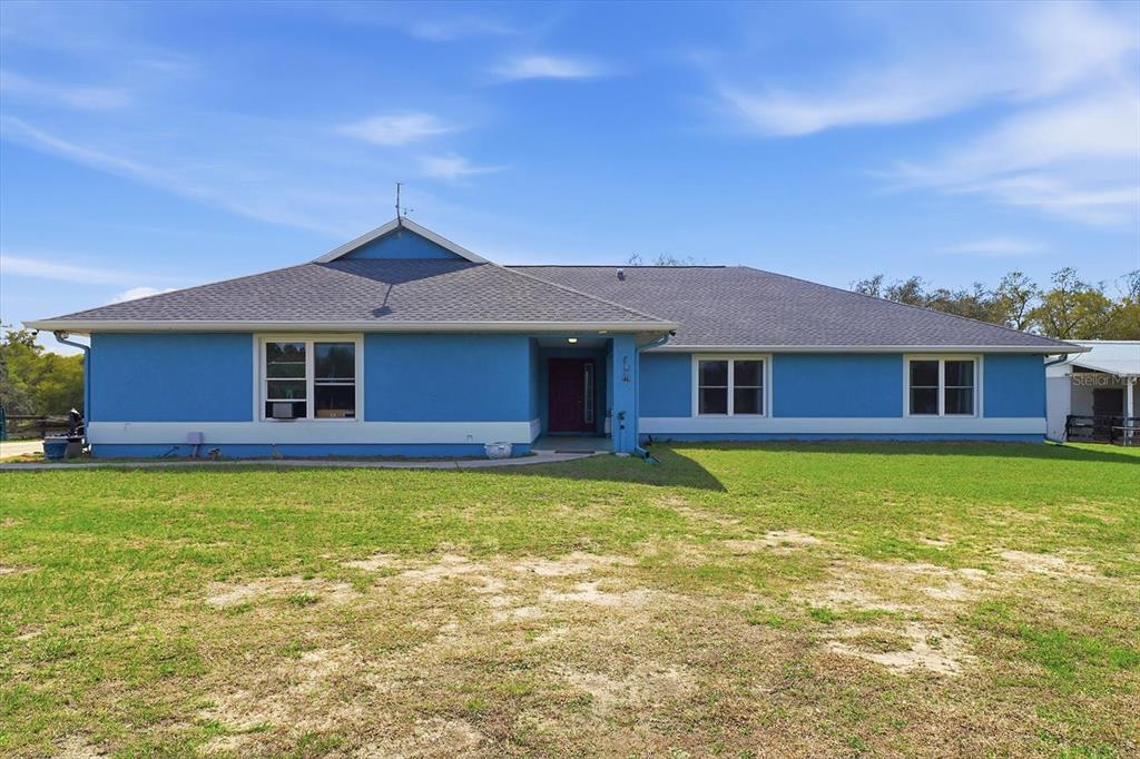 An aerial view shows a blue house situated on a large, fenced-in grassy pasture — 12524 SW 109TH PLACE, DUNNELLON, FL