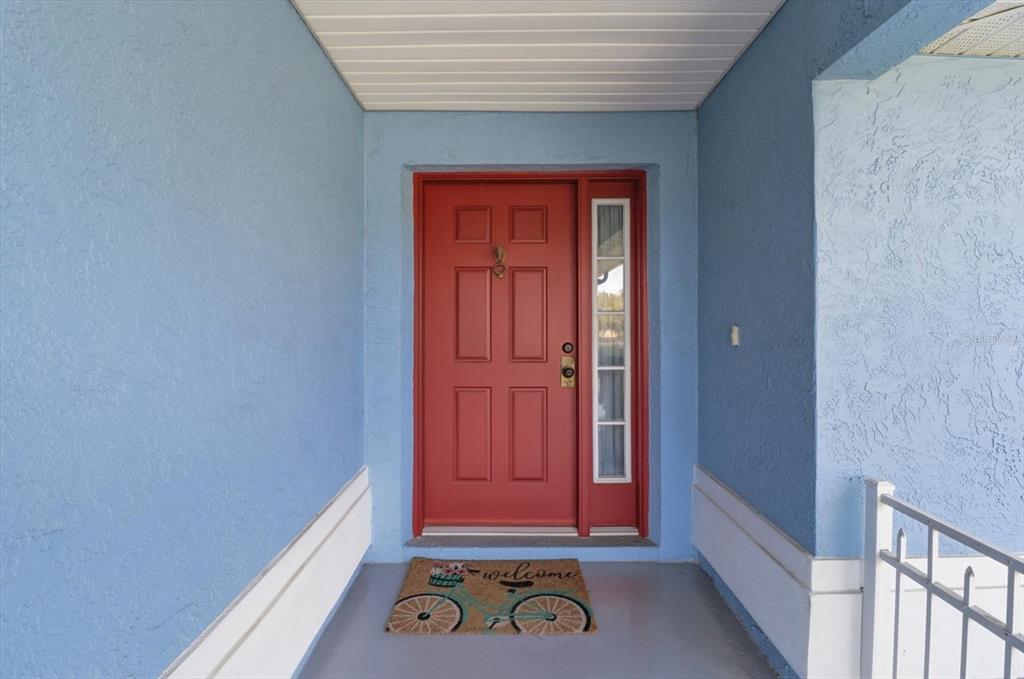 A red front door with a side window sits on a blue porch — 12524 SW 109TH PLACE, DUNNELLON, FL