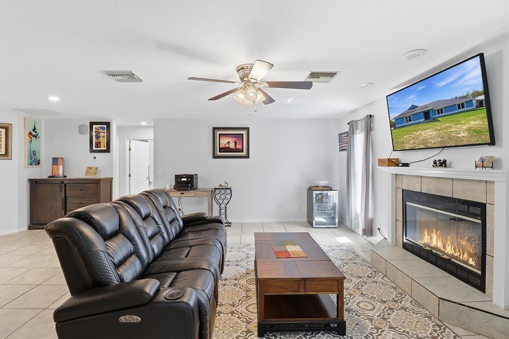 A living room features a leather sofa, a coffee table, and a fireplace with a television — 12524 SW 109TH PLACE, DUNNELLON, FL