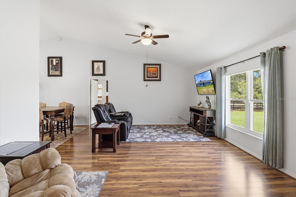 A living room with wood-look flooring, a ceiling fan, and a television mounted on the wall — 12524 SW 109TH PLACE, DUNNELLON, FL