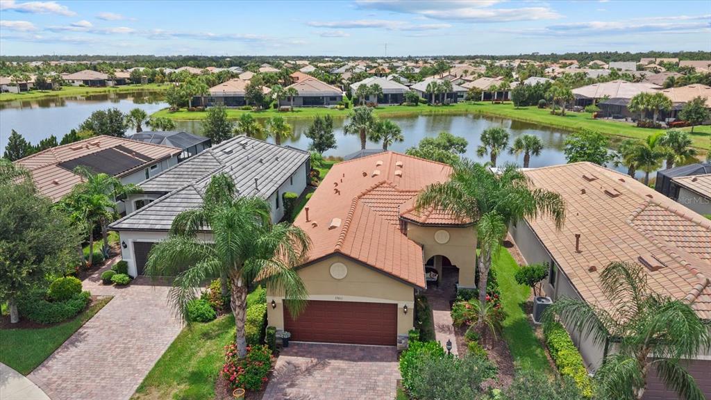 An aerial view shows a tan house with a terracotta roof next to a lake — 17011 HAMPTON FALLS TERRACE, LAKEWOOD RANCH, FL