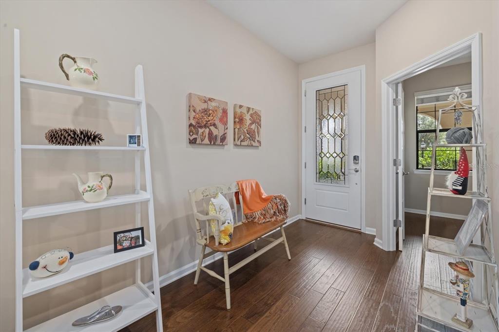 An entryway features a white ladder shelf, a wooden bench, and a glass-paneled front door — 17011 HAMPTON FALLS TERRACE, LAKEWOOD RANCH, FL