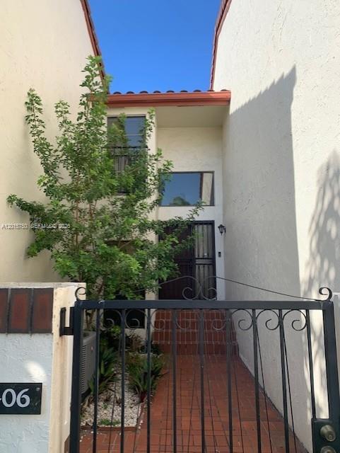 A gated entrance leads to a brick walkway and front door of a two-story townhouse — 341 Ives Dairy Rd # 06, Miami FL 33179, MIAMI, FL
