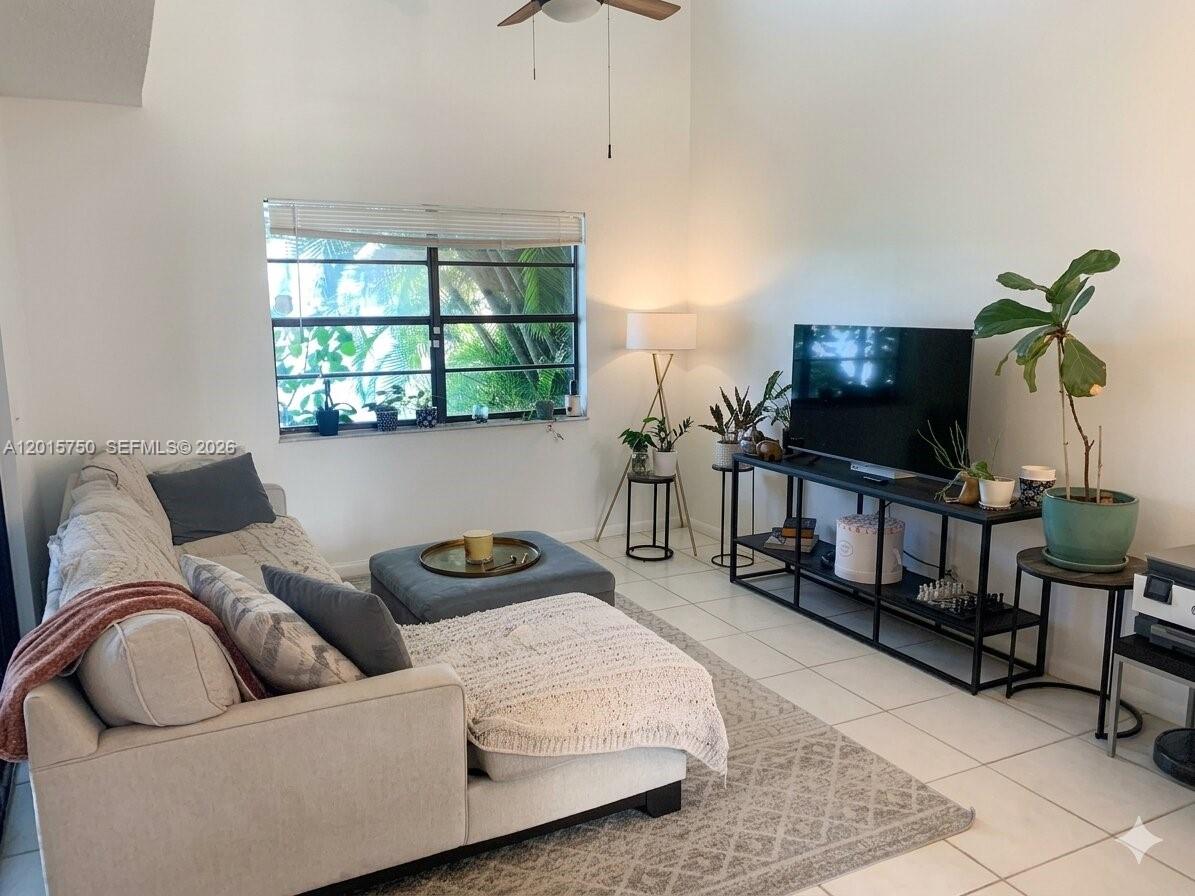 A living room features a sofa, ottoman, television on a console, and a large window — 341 Ives Dairy Rd # 06, Miami FL 33179, MIAMI, FL