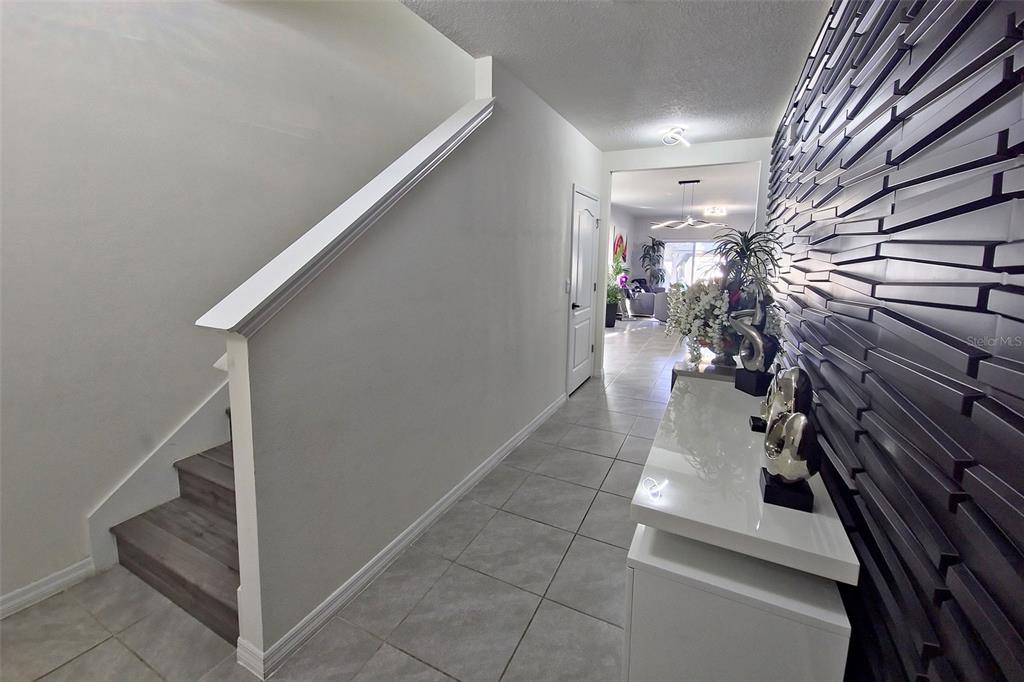 A hallway features a staircase, a textured accent wall, and a white console table — 1292 CASCADES AVENUE, DAVENPORT, FL