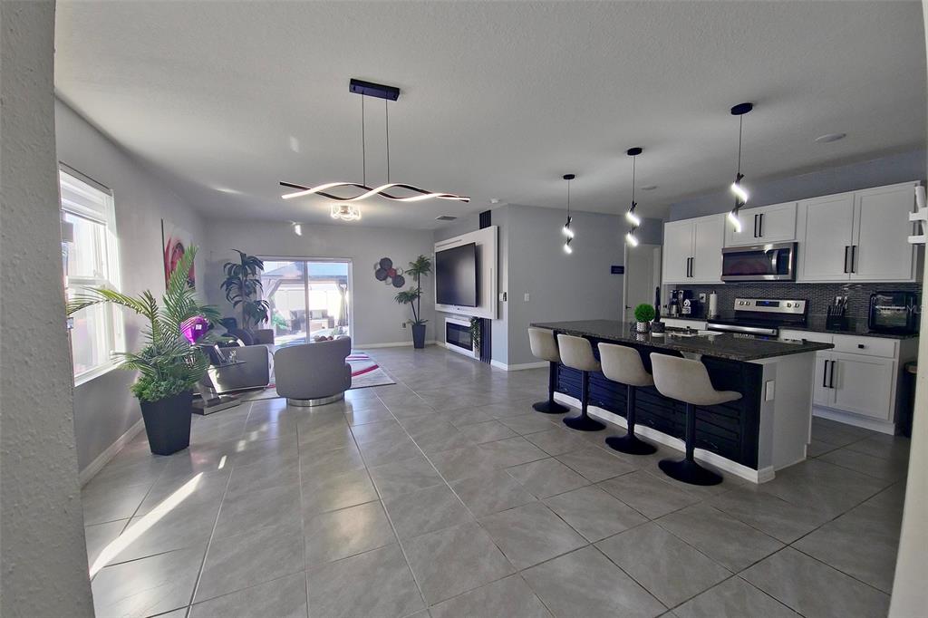 An open-concept kitchen and living area features tile flooring, white cabinetry, and modern lighting — 1292 CASCADES AVENUE, DAVENPORT, FL