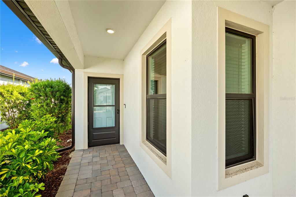 A covered entryway features a paved walkway, a dark-framed door, and two windows — 6600 SILVERSTAR DRIVE, SARASOTA, FL