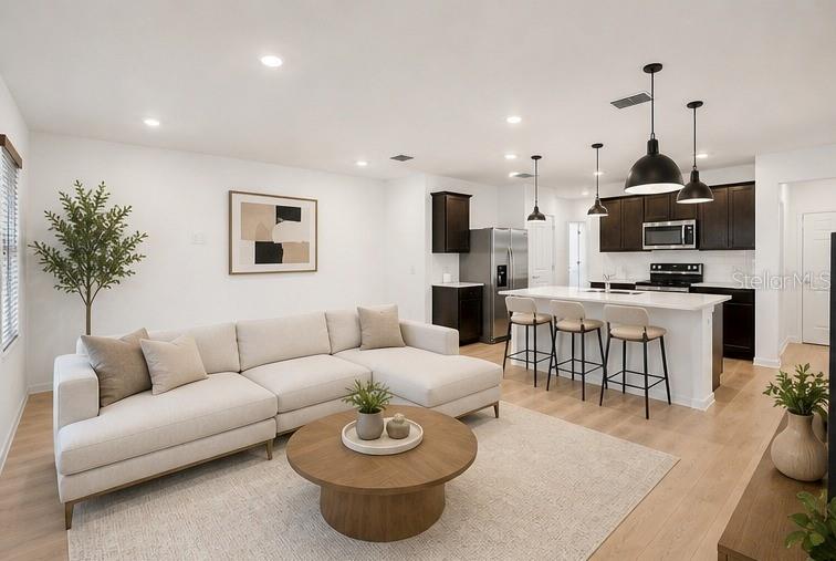 A modern open-concept living room features a light-colored sectional sofa, round coffee table, and kitchen — 6600 SILVERSTAR DRIVE, SARASOTA, FL