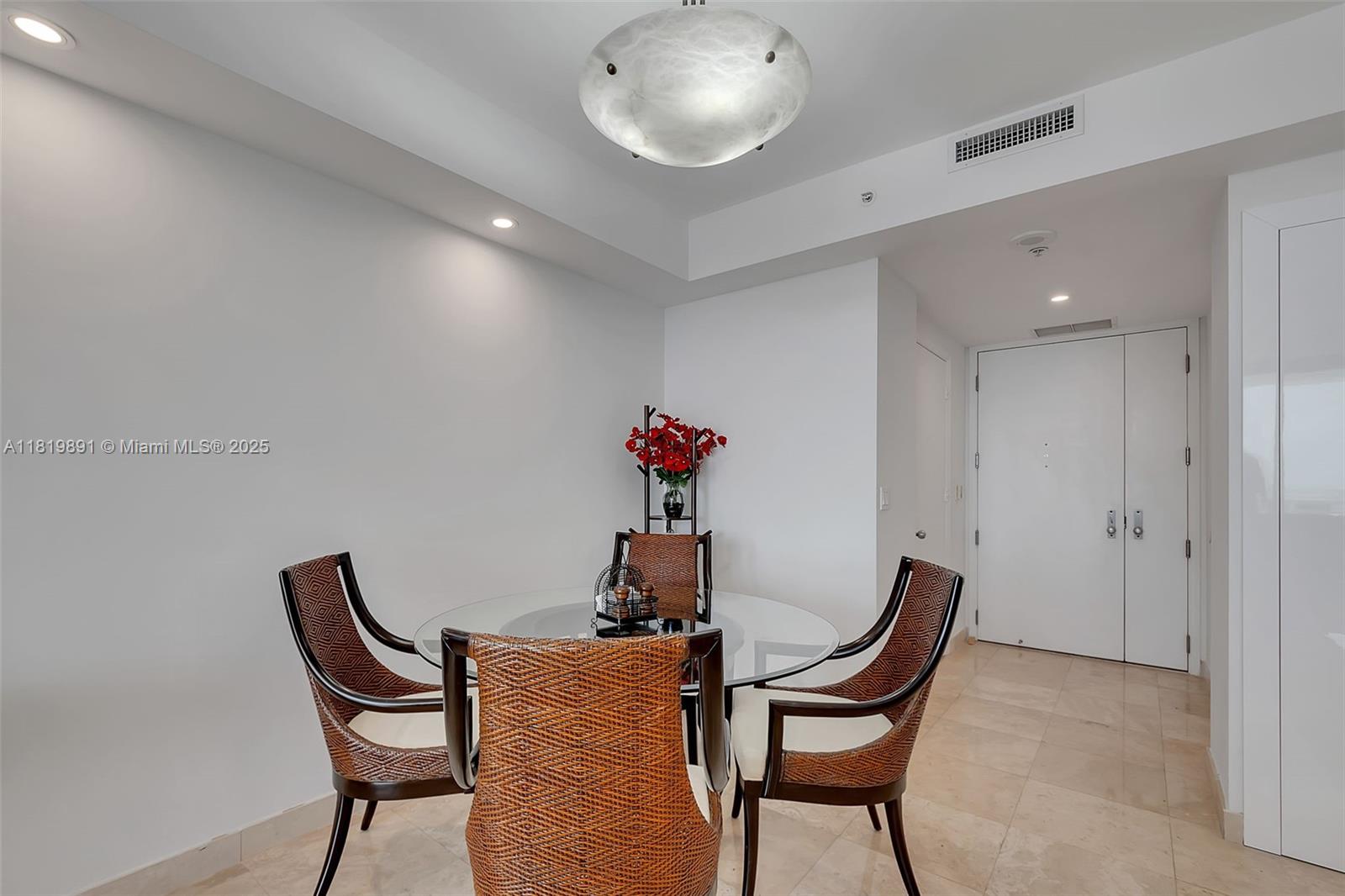 A dining area features a glass-topped table, four woven chairs, and a large ceiling light — 848 Brickell Key Dr # 1803, Miami FL 33131, MIAMI, FL