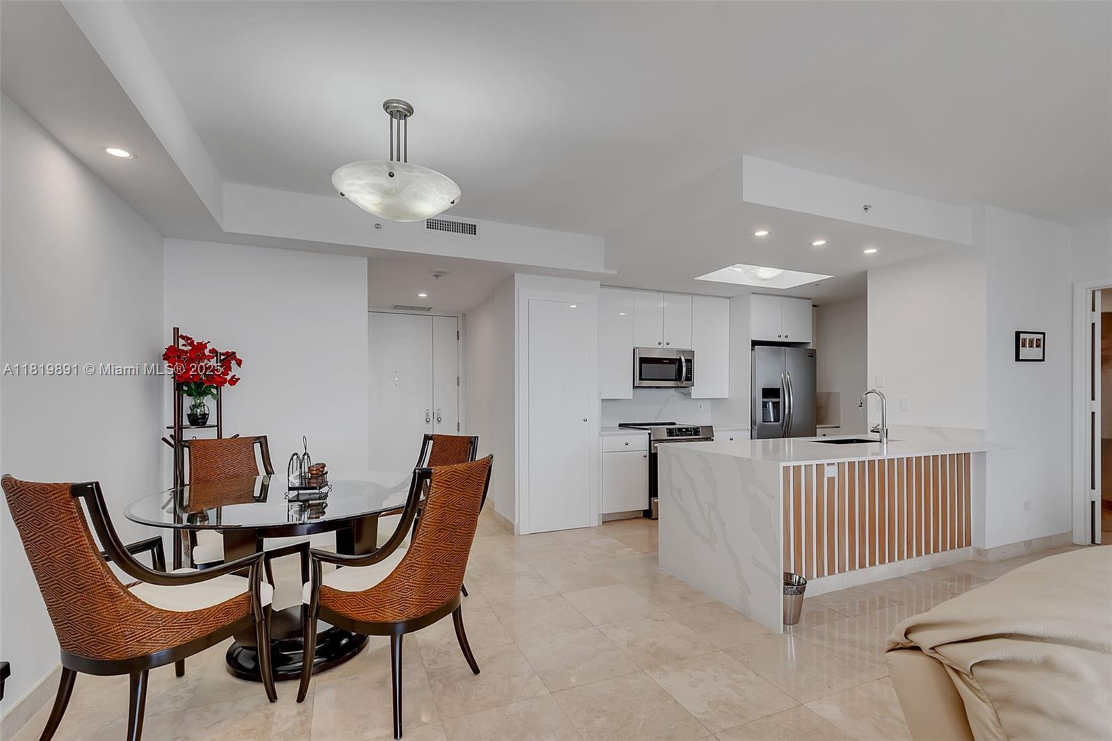 An open-concept kitchen and dining area features a glass table, marble island, and white cabinetry — 848 Brickell Key Dr # 1803, Miami FL 33131, MIAMI, FL