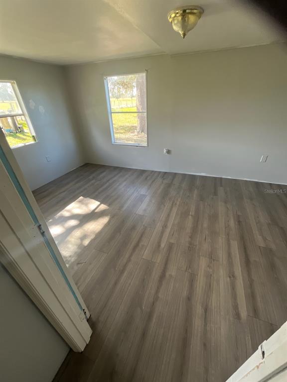 An empty bedroom features light gray walls, wood-look laminate flooring, and a flush-mount ceiling light — 20826 SUNRIDGE ROAD, GROVELAND, FL