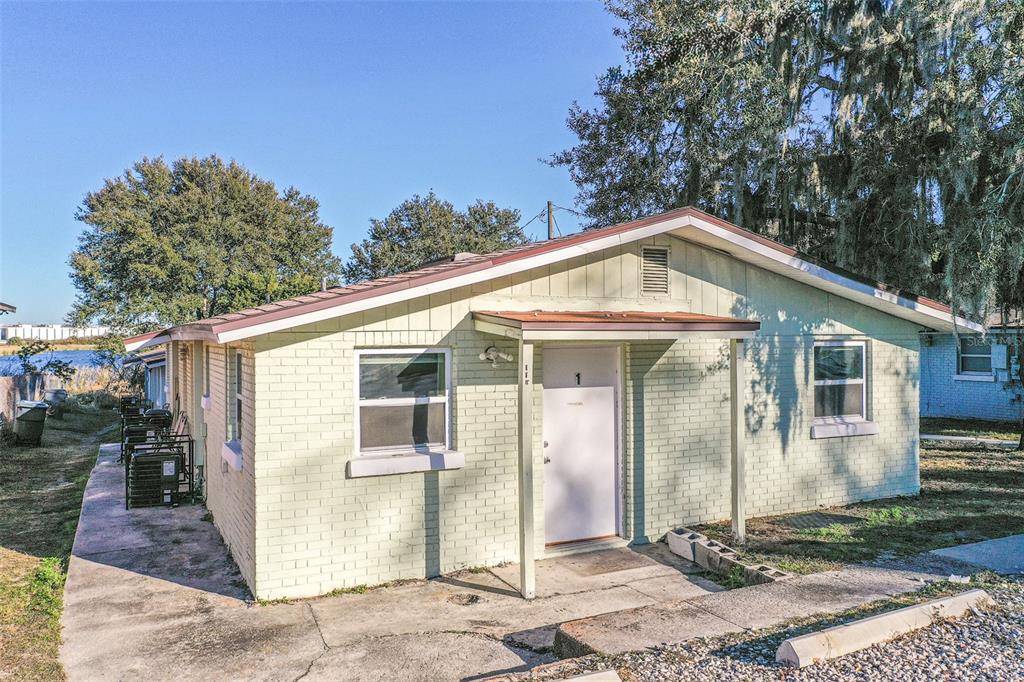 A single-story, light-colored brick building with a white door and a small covered porch — 114 E NORTHSIDE DRIVE UNIT 3, LAKE WALES, FL