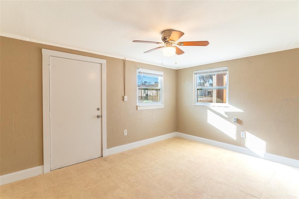 An empty room with tan walls, tile flooring, two windows, and a ceiling fan — 114 E NORTHSIDE DRIVE UNIT 3, LAKE WALES, FL