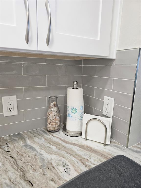 A kitchen counter features a gray subway tile backsplash, white cabinets, and a granite countertop — 3100 GULF BOULEVARD UNIT 221, BELLEAIR BEACH, FL