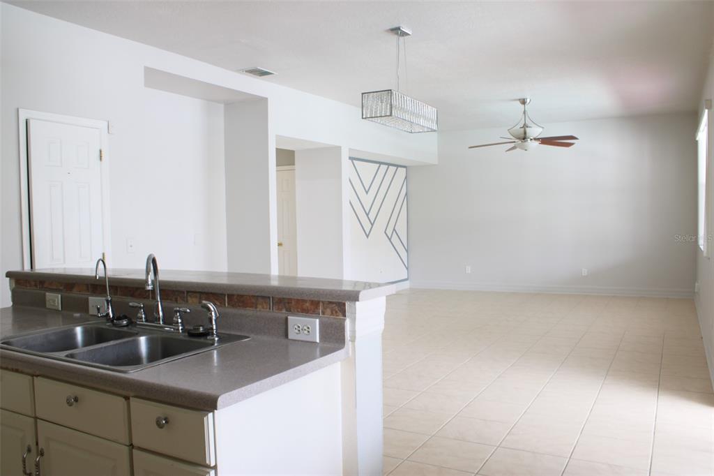 A kitchen sink and counter overlook an open-concept living area with tile flooring — 1338 BLACKWATER POND DRIVE, ORLANDO, FL