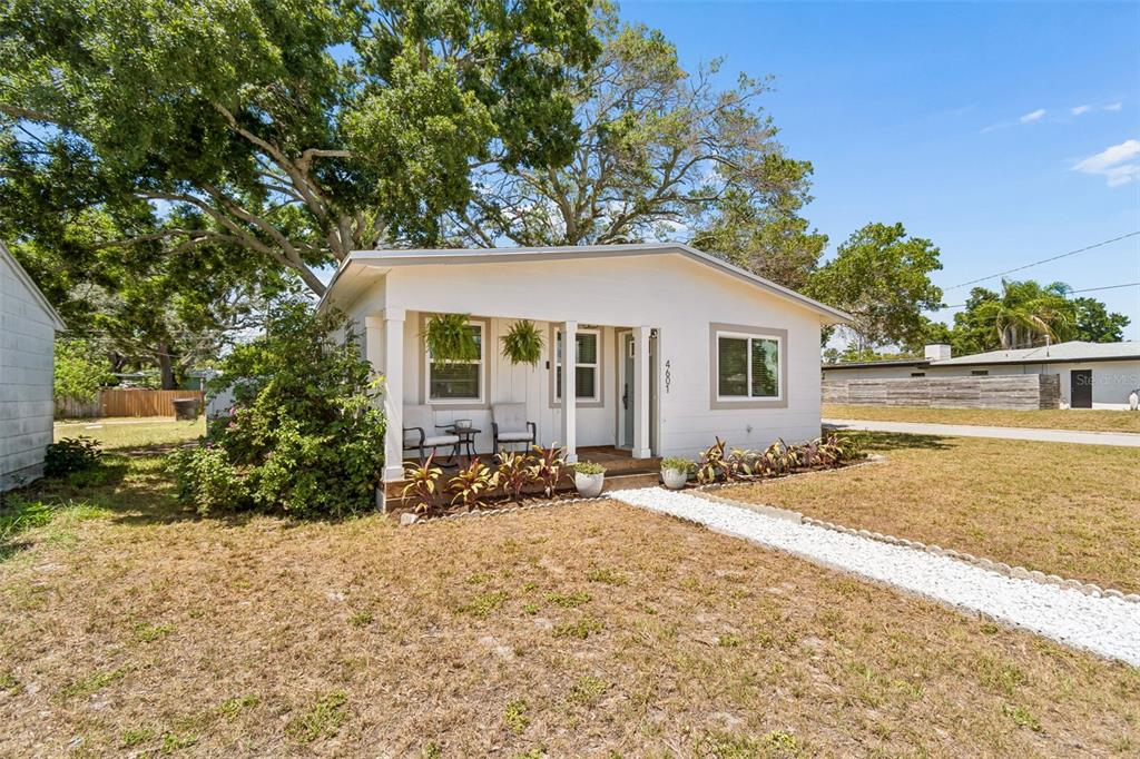A small, white, single-story house features a covered front porch and a white gravel walkway — 4601 16TH AVENUE N, ST PETERSBURG, FL