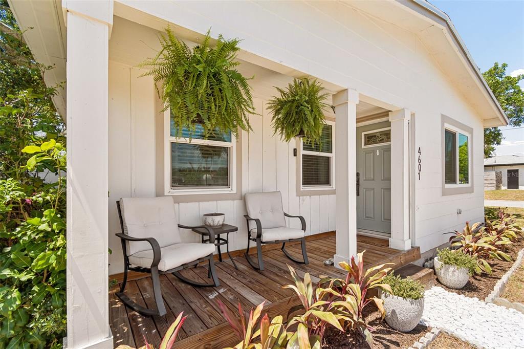 A covered front porch features two rocking chairs, hanging ferns, and a light-colored door — 4601 16TH AVENUE N, ST PETERSBURG, FL