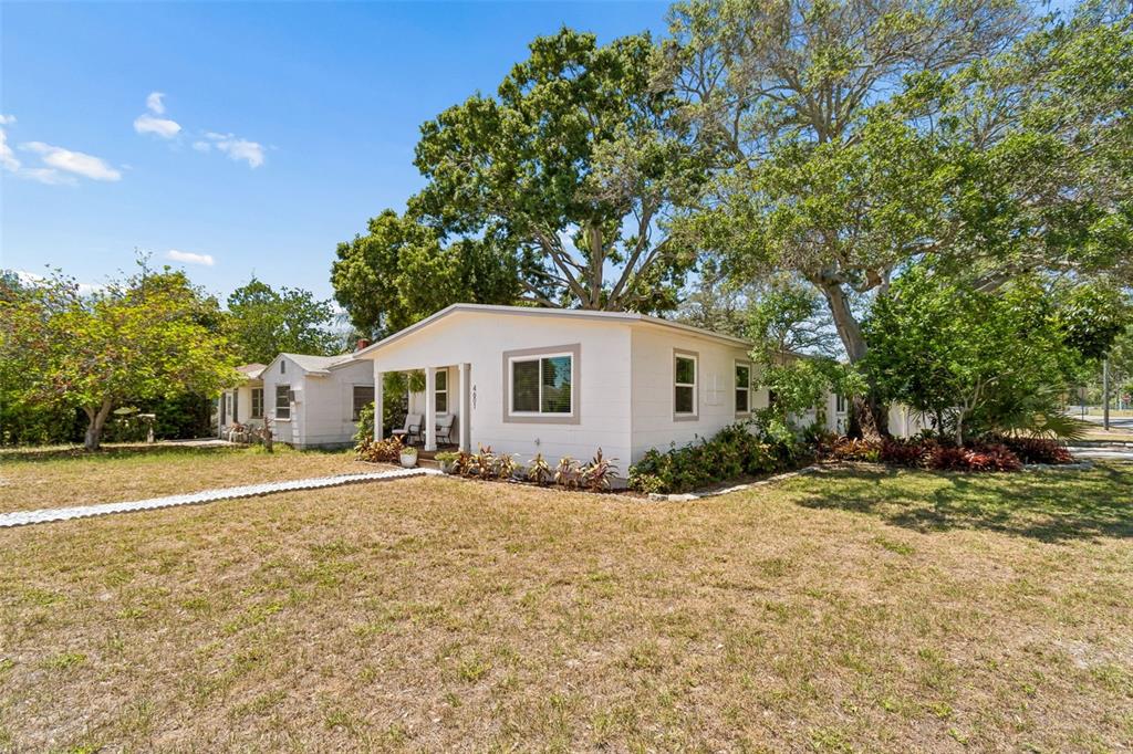 A white single-story house with a front porch sits on a grassy lot with trees — 4601 16TH AVENUE N, ST PETERSBURG, FL