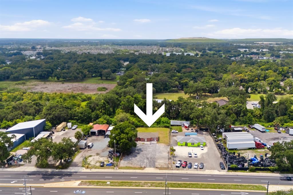 An aerial view shows a small, single-story building situated between two commercial properties along a road — 7113 CAUSEWAY BOULEVARD, TAMPA, FL