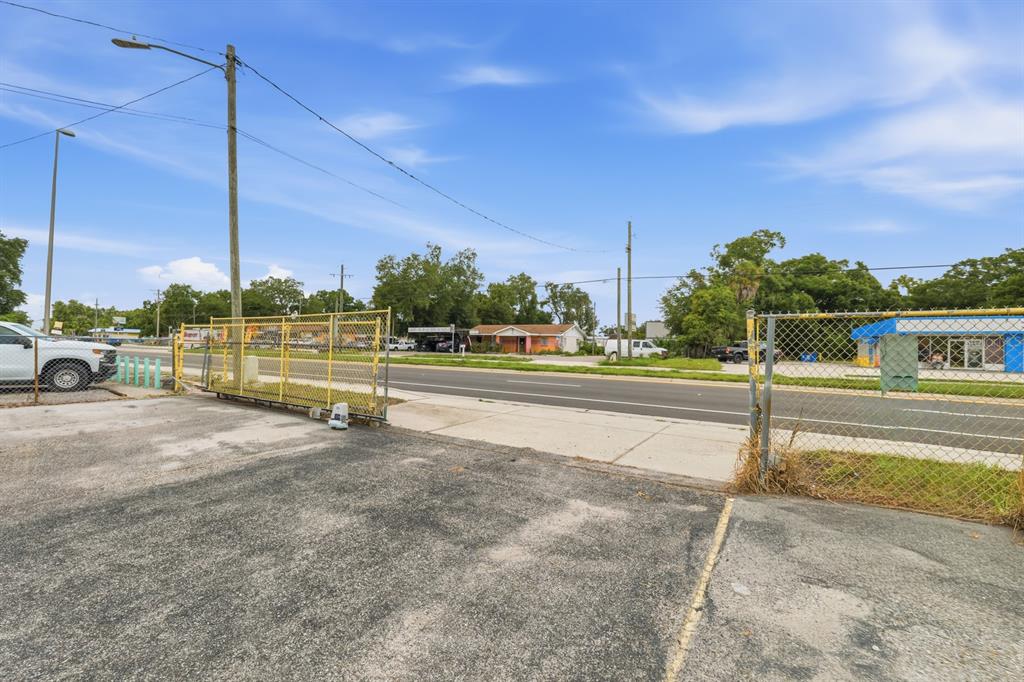 A view of a paved lot with a chain-link fence and gate facing a street — 7113 CAUSEWAY BOULEVARD, TAMPA, FL