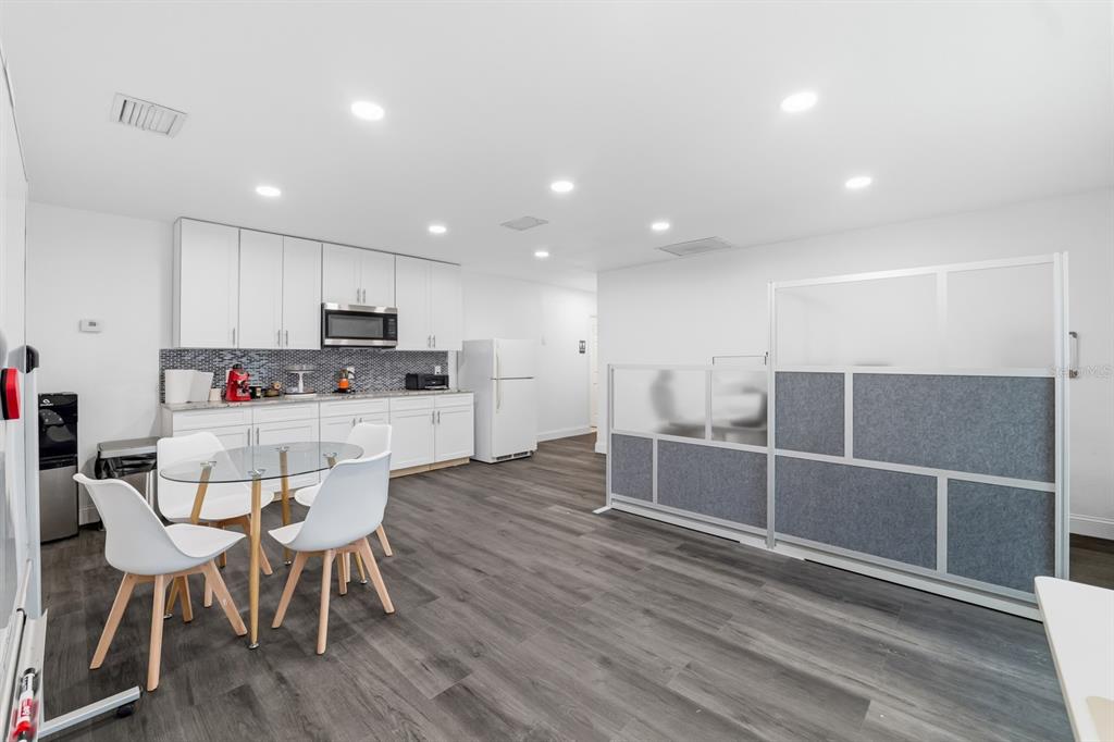 A kitchen area features white cabinets, a glass dining table, and a grey office partition — 7113 CAUSEWAY BOULEVARD, TAMPA, FL