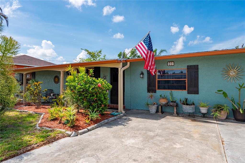 A teal one-story house features a front porch, a concrete driveway, and an American flag — 611 BONITA COURT, PUNTA GORDA, FL