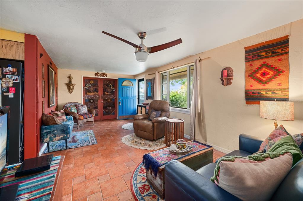 A living room with terracotta tile floors, a blue front door, and eclectic southwestern decor — 611 BONITA COURT, PUNTA GORDA, FL