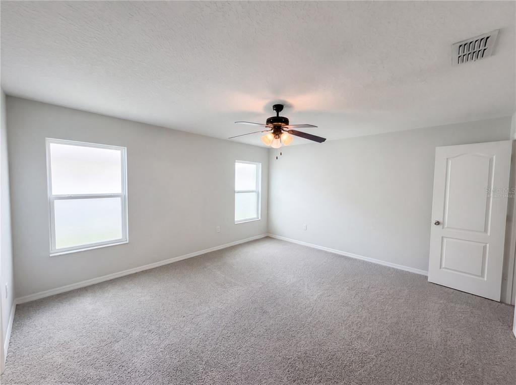 A bedroom with light gray walls, gray carpeting, two windows, and a ceiling fan — 4272 MOON SHADOW LOOP, MULBERRY, FL