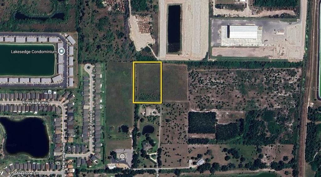 This aerial map shows a rectangular vacant lot highlighted in yellow near residential and industrial areas — 3100 ROWLAND DRIVE UNIT Tract B, PUNTA GORDA, FL