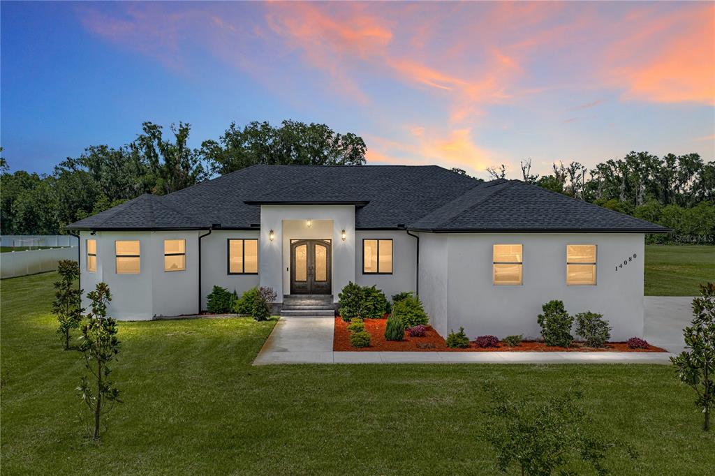 A single-story white house with a dark roof and a central entryway at sunset — 14080 SYDNEY ROAD, DOVER, FL