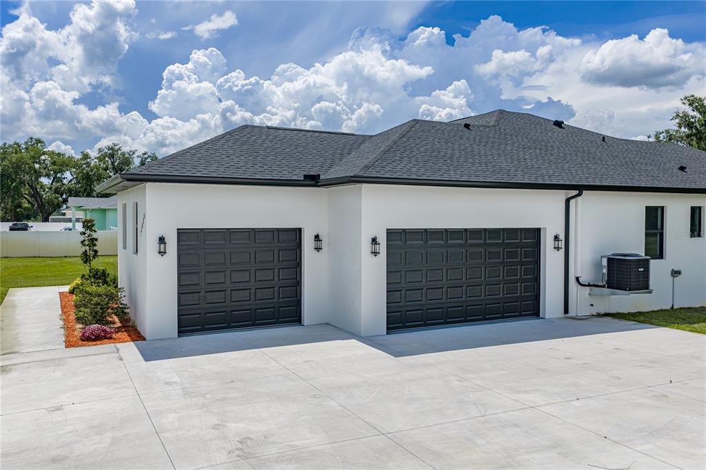 The exterior of a house features two dark garage doors and a concrete driveway — 14080 SYDNEY ROAD, DOVER, FL