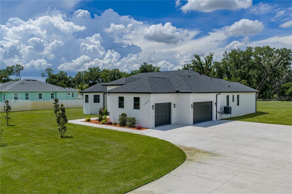 A white house with a dark shingled roof and a three-car garage sits on grass — 14080 SYDNEY ROAD, DOVER, FL