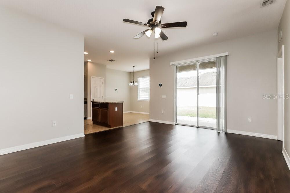 An open-concept living room features dark wood flooring, light gray walls, and a sliding glass door — 925 KRENSON WOODS ROAD, LAKELAND, FL