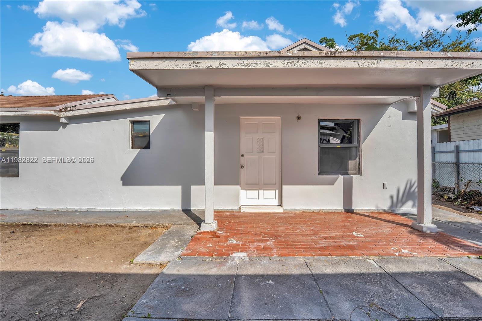 A single-story house exterior features a white facade, a covered porch, and a brick patio — 2428 NW 28th St REAR, Miami FL 33142, MIAMI, FL