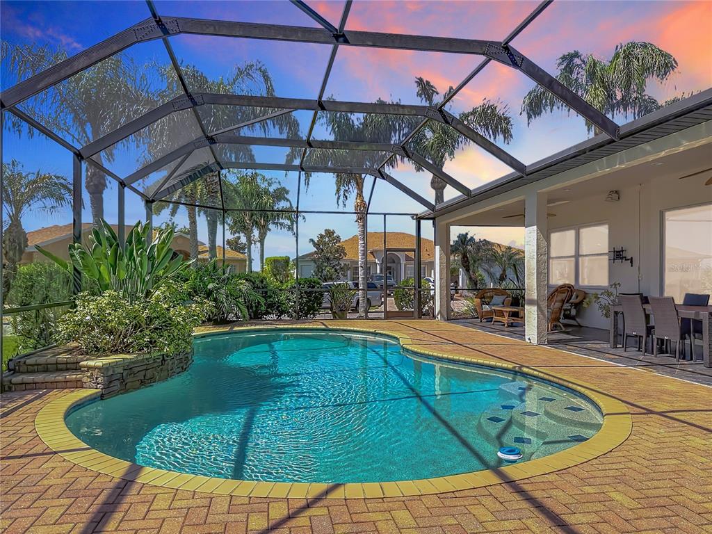 A swimming pool with a stone planter sits inside a screened-in patio with brick pavers — 4231 COCONUT DRIVE, LAKE WALES, FL