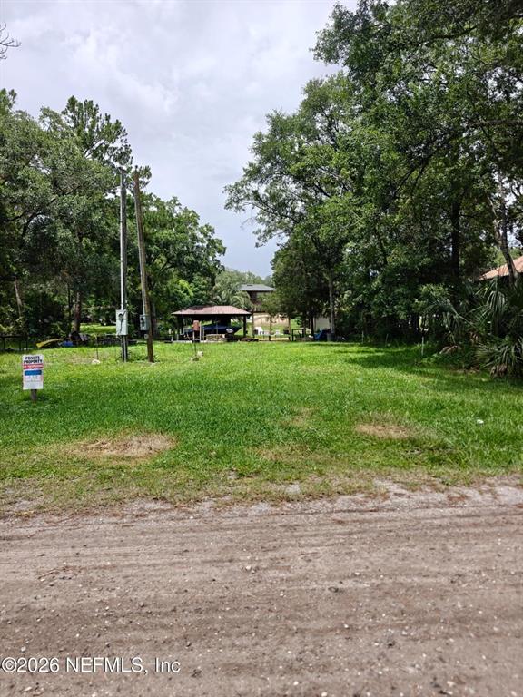 A grassy, wooded lot features a small pavilion in the distance and a utility pole — 5235 HIDE-A-WAY DRIVE, JACKSONVILLE, FL