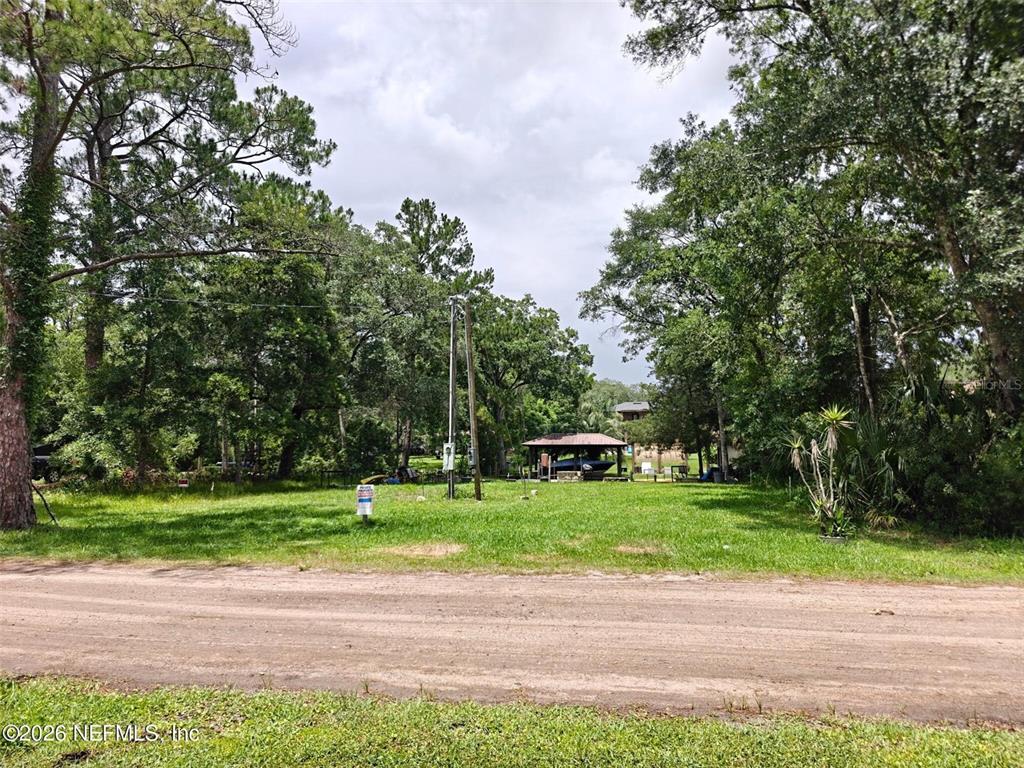 A grassy, tree-lined vacant lot features a small boat shelter in the background — 5235 HIDE-A-WAY DRIVE, JACKSONVILLE, FL