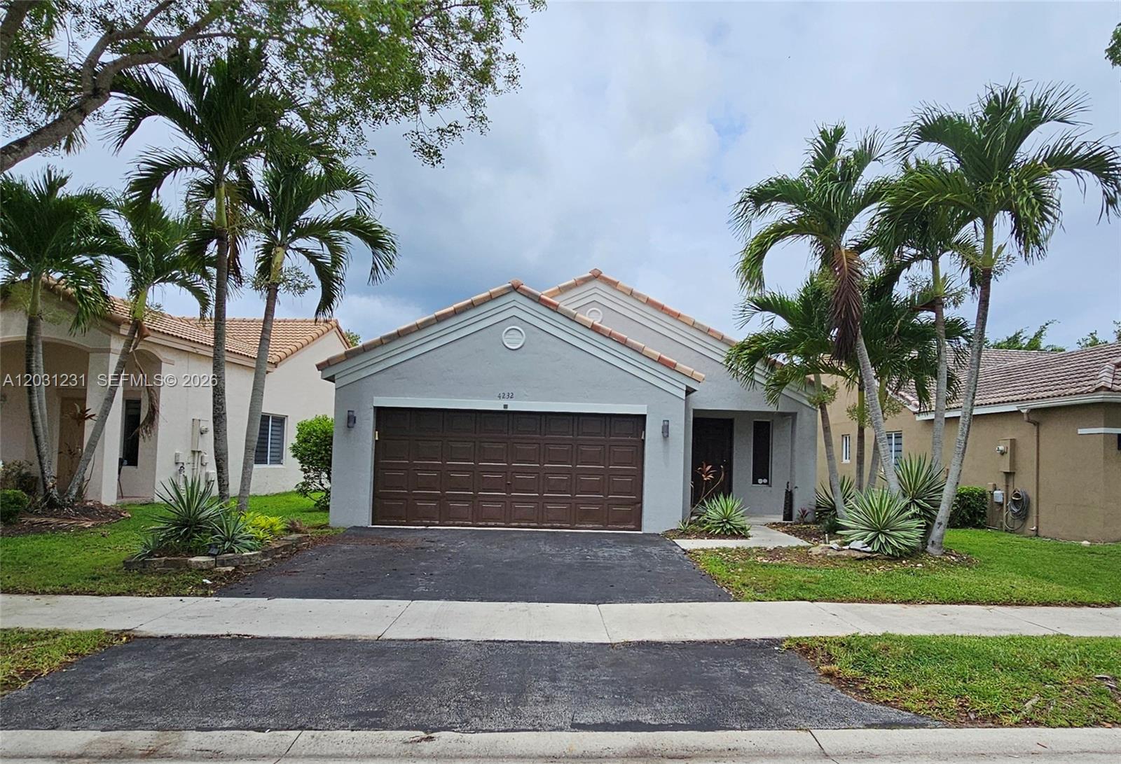 A single-story house with a brown garage door, gray exterior, and palm trees in front — 4232 Mahogany Ridge Dr, Weston FL 33331, WESTON, FL