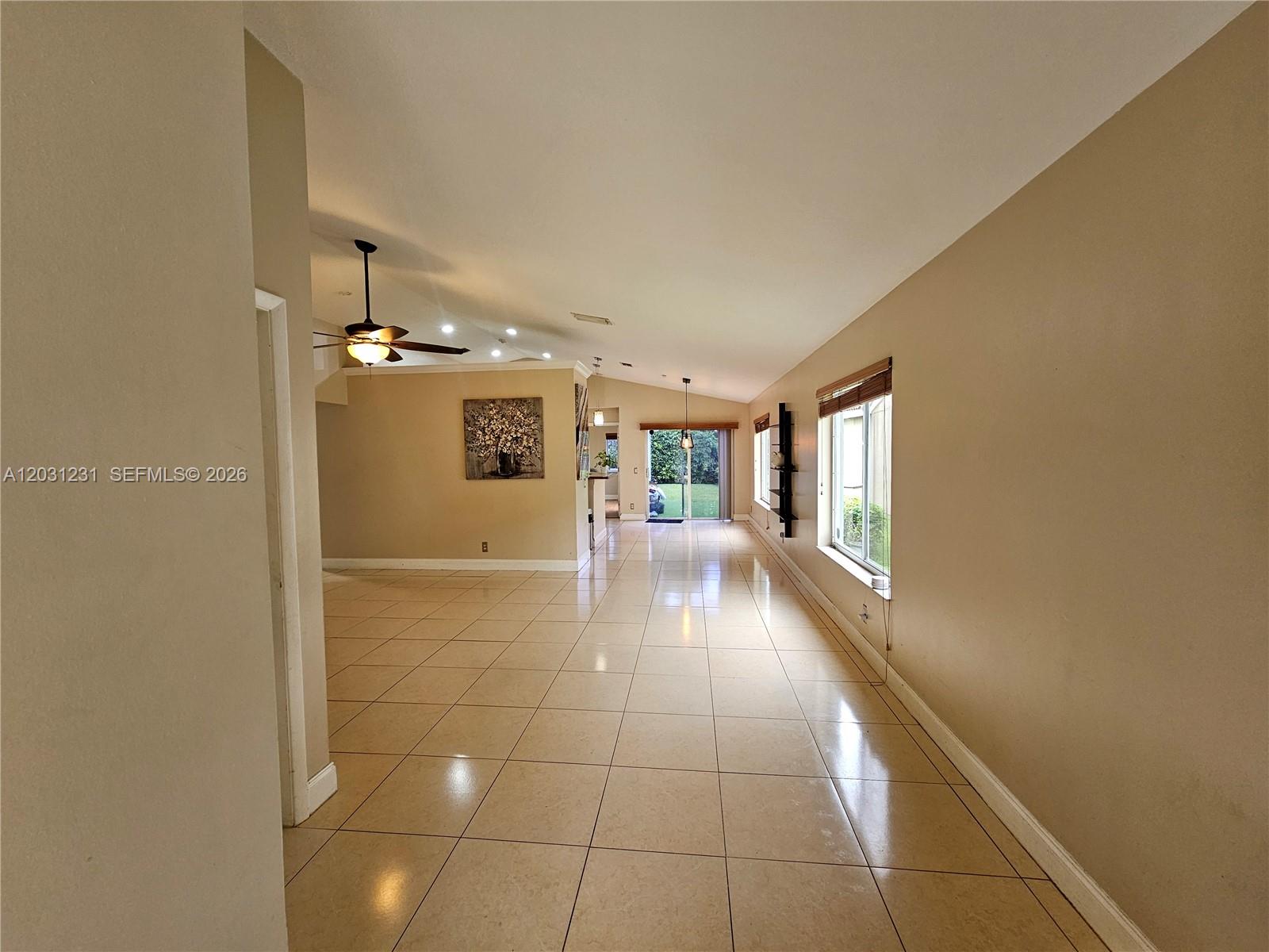 A spacious room with light-colored tile flooring, beige walls, a ceiling fan, and sliding doors — 4232 Mahogany Ridge Dr, Weston FL 33331, WESTON, FL