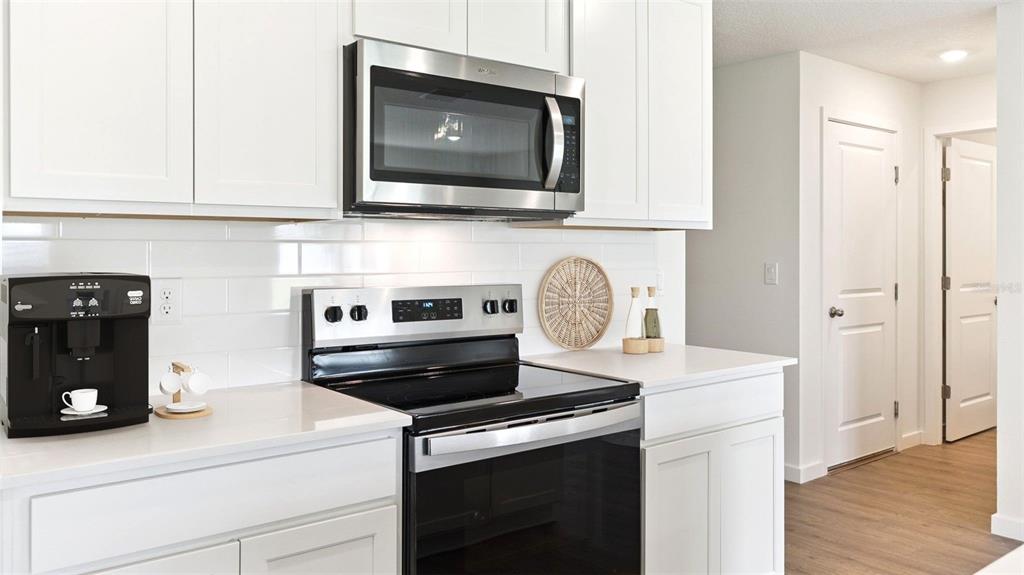 A kitchen features white cabinets, stainless steel appliances, and a white subway tile backsplash — 433 CARIBBEAN COURT, KISSIMMEE, FL