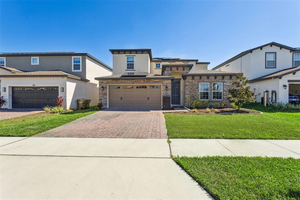 A two-story suburban house with a stone facade, a paved driveway, and a green lawn — 1111 LONE PALM WAY, ST CLOUD, FL