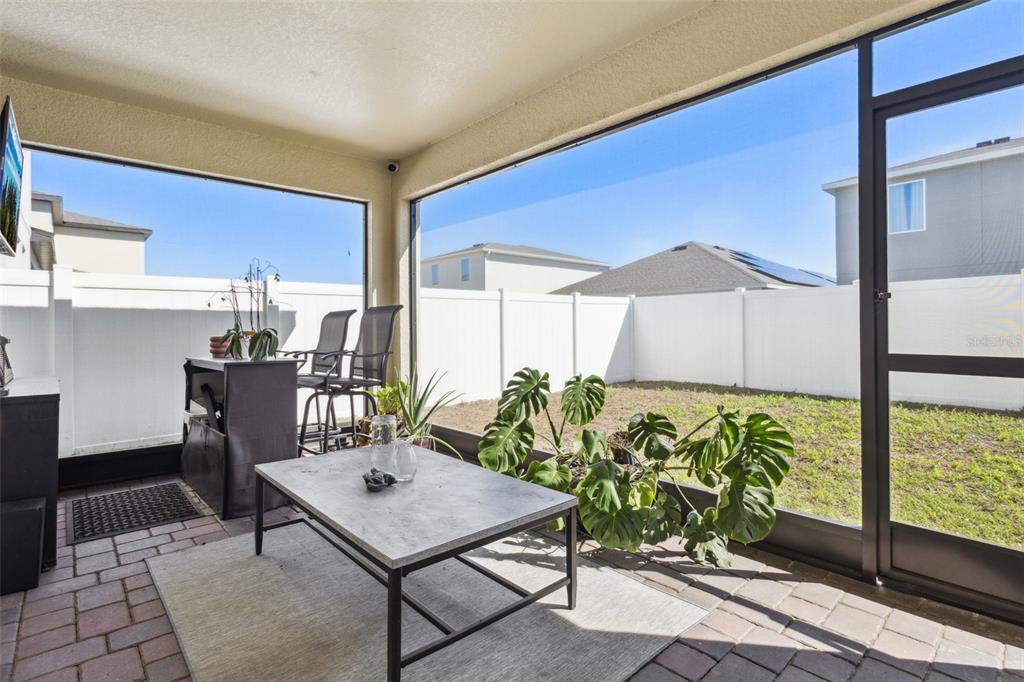 A screened-in patio features a stone-topped coffee table, a potted plant, and a fenced yard — 1111 LONE PALM WAY, ST CLOUD, FL