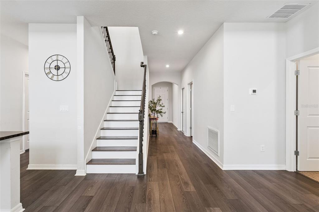 An interior view of a foyer featuring a staircase, hardwood flooring, and white walls — 1111 LONE PALM WAY, ST CLOUD, FL