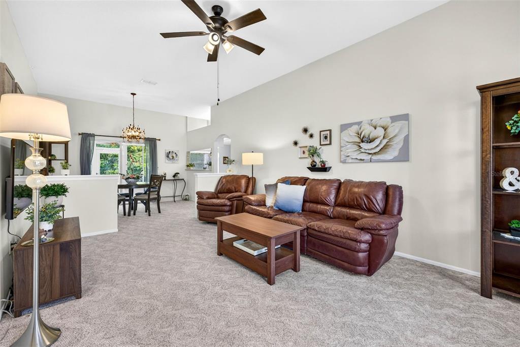 A living room with beige walls, carpeted floors, a leather sofa, and a ceiling fan — 4233 AVANTI CIRCLE, NEW PORT RICHEY, FL