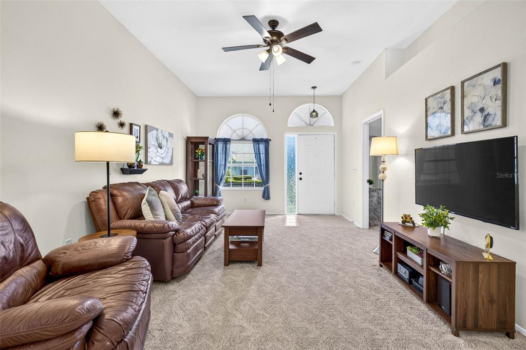 A living room features a brown leather sofa, a television, and a ceiling fan — 4233 AVANTI CIRCLE, NEW PORT RICHEY, FL