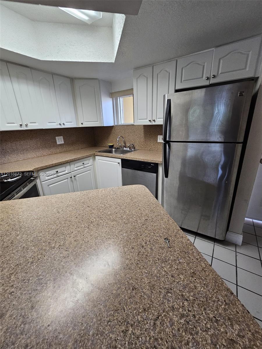 A kitchen features white cabinets, speckled countertops, stainless steel appliances, and a skylight — 8245 Lake Dr # 401, Doral FL 33166, DORAL, FL