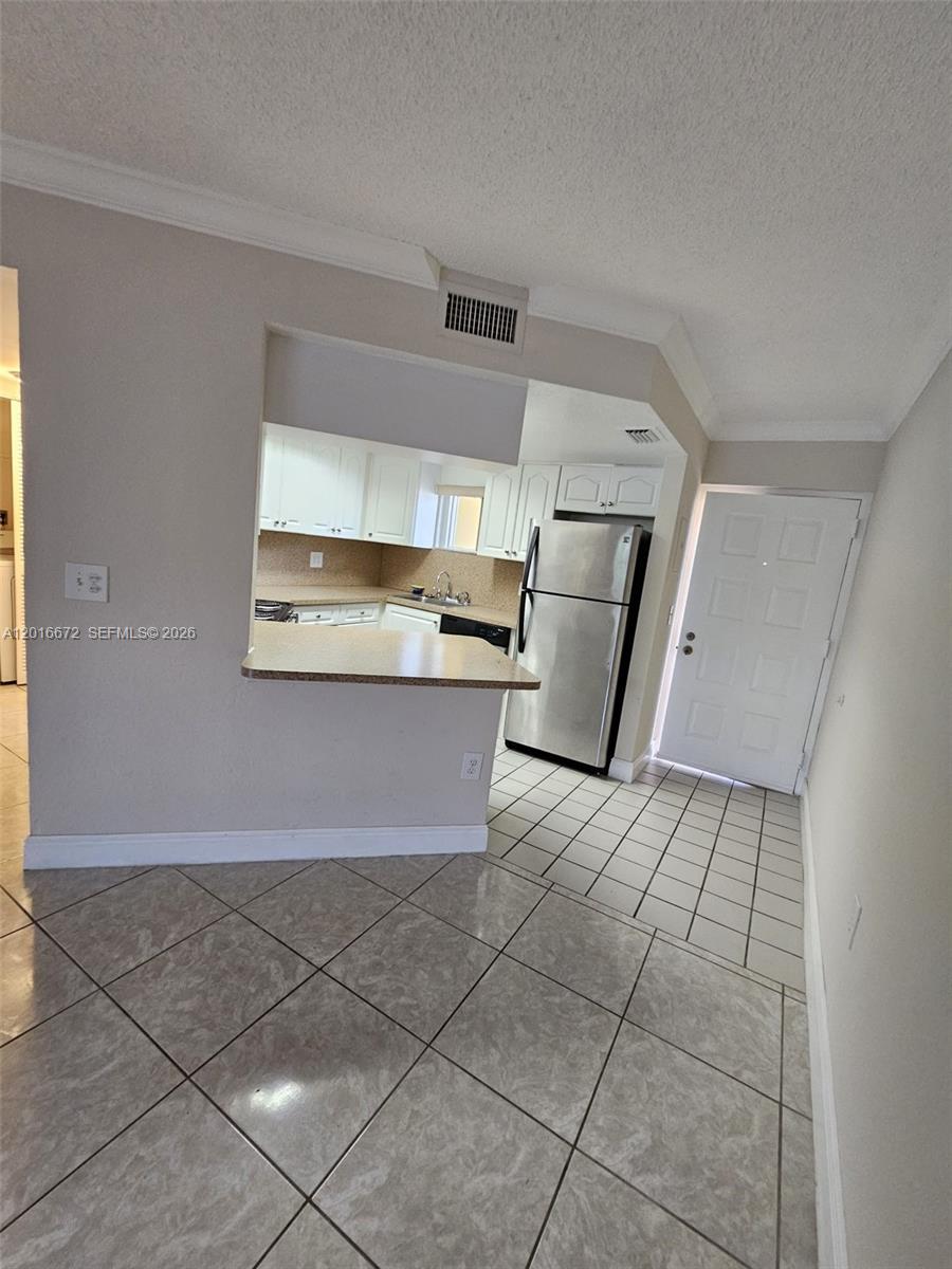A kitchen with white cabinets and stainless steel appliances is visible through a wall opening — 8245 Lake Dr # 401, Doral FL 33166, DORAL, FL