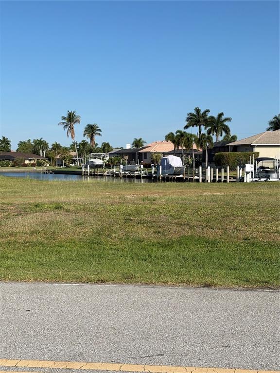 A grassy lot overlooks a canal with boat docks and residential houses in the background — 534 MACEDONIA DRIVE, PUNTA GORDA, FL