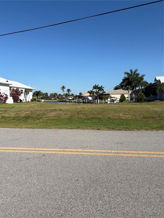 A vacant grassy lot sits between two houses near a canal with docked boats — 534 MACEDONIA DRIVE, PUNTA GORDA, FL